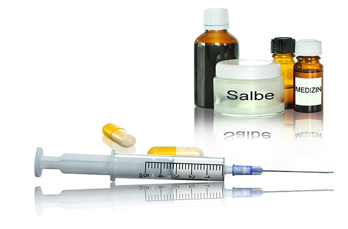 Vorstufen von Gebärmutterhalskrebs können mit konservativer Therapie schonend behandelt werden. Tabletten, Salbe, Medizinflaschen und Spritze auf weißem leicht spiegelnden Hintergrund als Medikamente zur konservativen Behandlung.